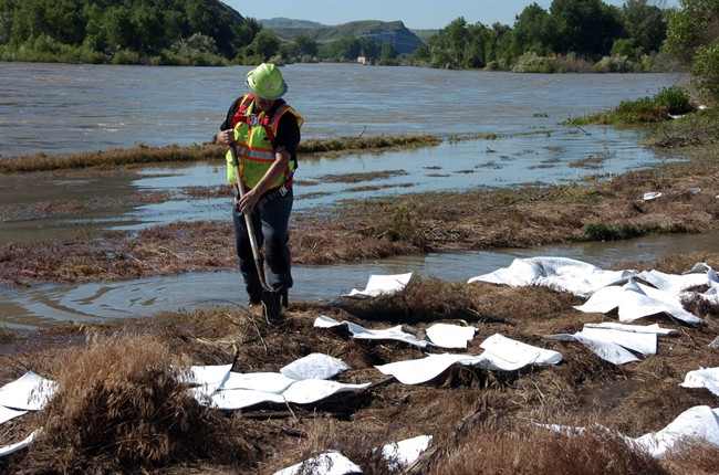 An ExxonMobil contractor cleans up oil along the banks of the Yellowstone River in Billings, Mont., Sunday, July 3, 2011.