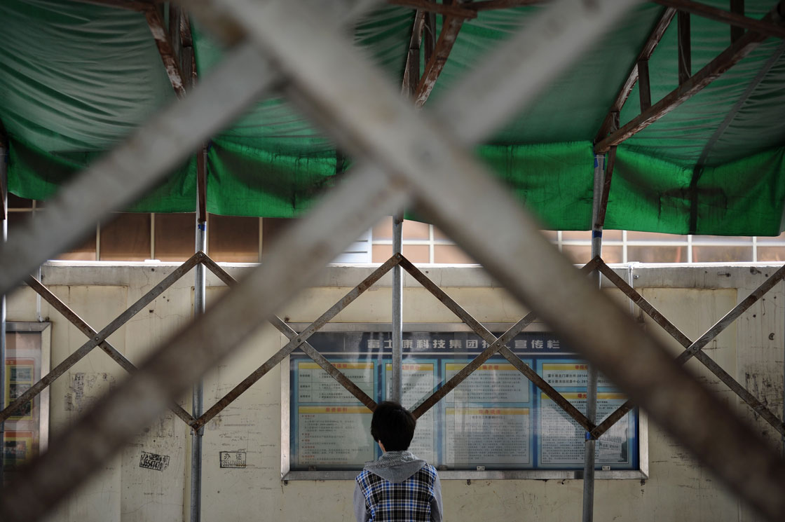 A young man reads a bulletin board at a Foxconn recruitment center in Shenzhen, south China's Guangdong province. 
