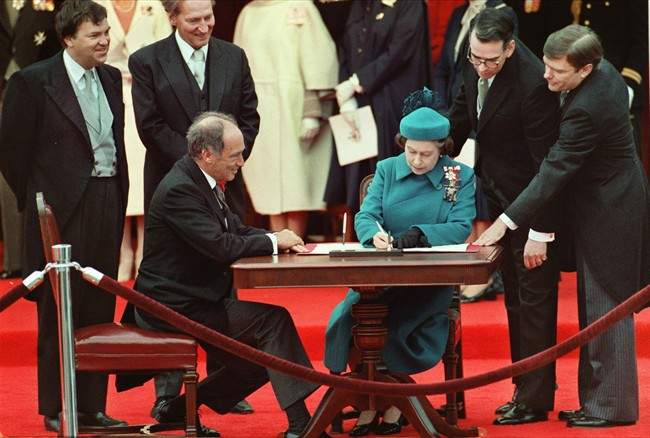 Queen Elizabeth II signs Canada's constitutional proclamation in Ottawa on April 17, 1982 as Prime Minister Pierre Trudeau looks on.