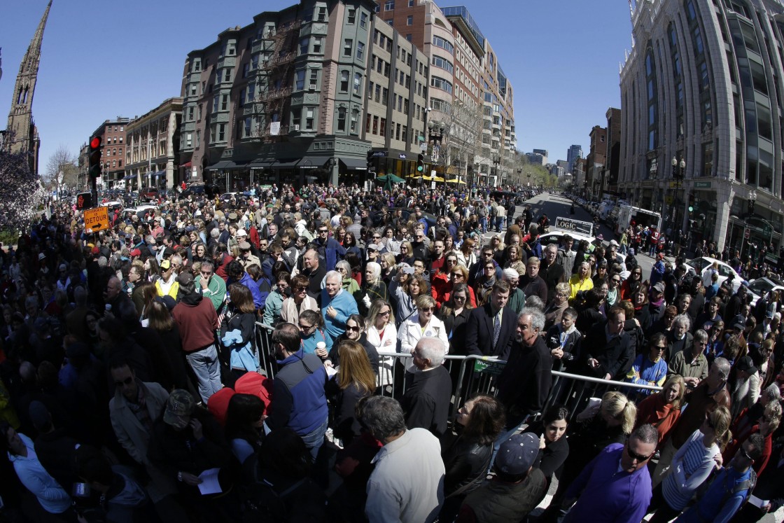 In this photograph made with a fisheye lens, people attend an interfaith service held near a makeshift memorial on Boylston Street, near the finish line of the Boston Marathon, Sunday, April 21, 2013, in Boston. The city is coping in the aftermath of the marathon bombing. (Julio Cortez / AP Photo)