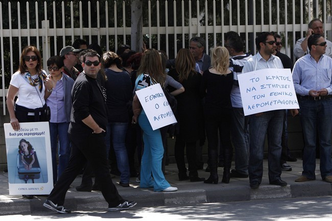 Employees of Cyprus Airways with banners, left, reading in Greek "travelling with my own airlines", right, "the state support the state-owned carrier" during a demonstration outside of the presidential palace in Nicosia, Cyprus, Wednesday, April 10, 2013.