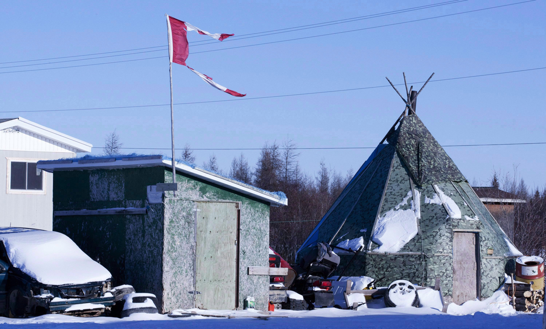 File photo - The remains of a Canadian flag can be seen flying over a building in Attawapiskat, Ont., on November 29, 2011. 
