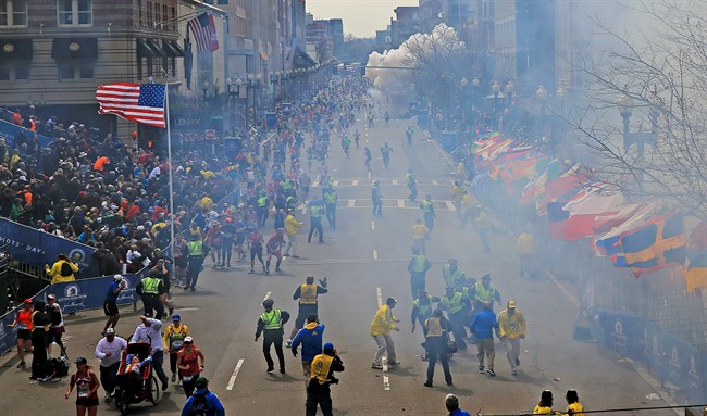 People react as an explosion goes off near the finish line of the 2013 Boston Marathon in Boston, Monday, April 15, 2013.  (AP Photo/The Boston Globe, David L Ryan) .