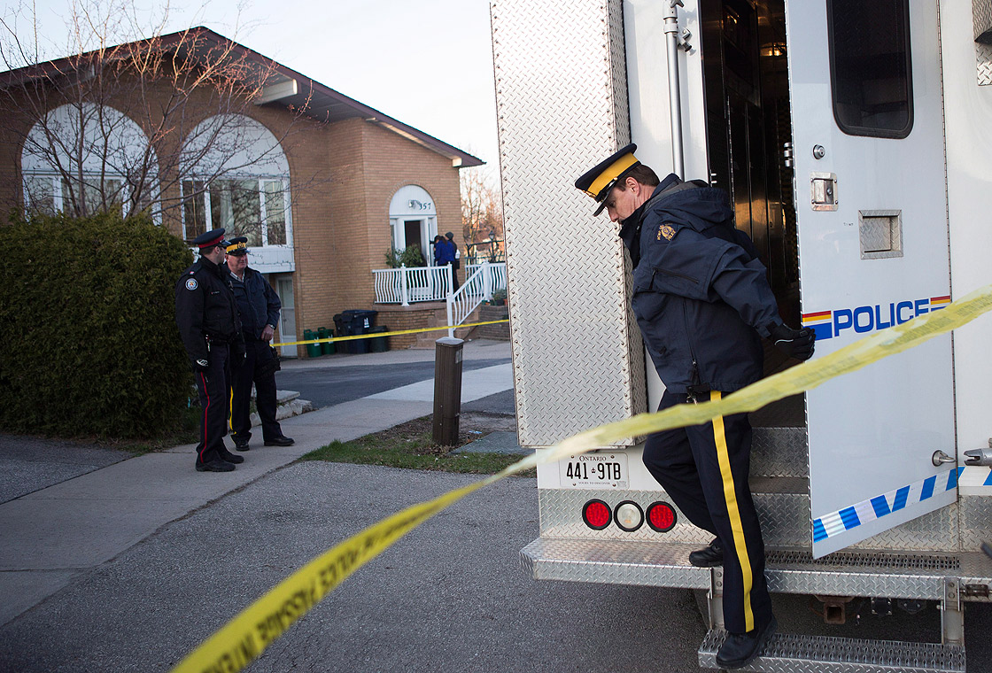 RCMP officers stand outside the Toronto home of one of the two men accused of plotting a terror attack on a rail target, on Monday April 22, 2013.