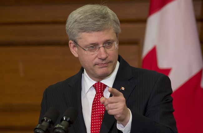 Canadian Prime Minister Stephen Harper points to the door as he speaks to members of Caucus on Parliament Hill Tuesday May 21, 2013 in Ottawa.