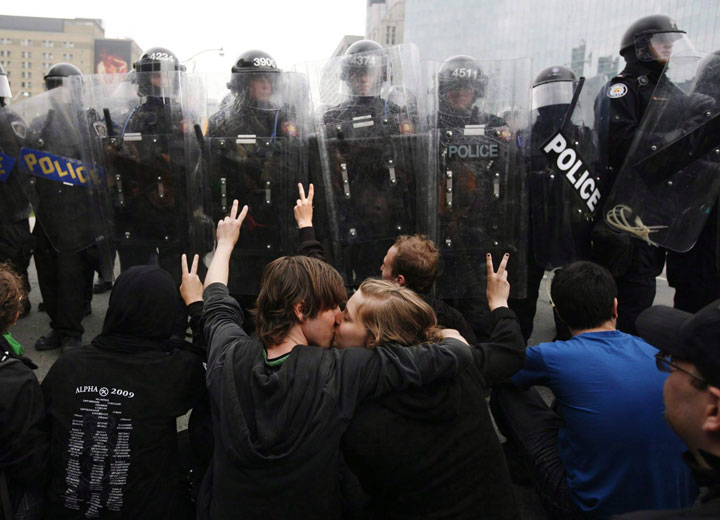 Two activists kiss while protesting in front of a line of riot police during the G20 Summit in Toronto Saturday, June 26, 2010. 