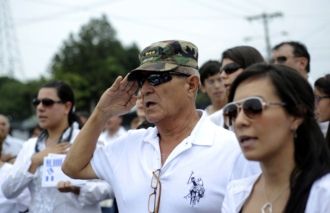 Supporters of former Guatemalan de facto President (1982-1983), retired General Jose Efrain Rios Montt, sing the national anthem during a protest against the latter's prosecution, outside a military prison at Matamoros in Guatemala City on May 12, 2013. Rios Montt was found guilty of genocide and war crimes on May 10 and sentenced to 80 years in prison in a landmark ruling stemming from massacres of indigenous people in his country's long civil war. Rios Montt thus became the first Latin American convicted of trying to exterminate an entire group of people in a brief but particularly gruesome stretch of a war that started in 1960, lasted 36 years and left around 200,000 people dead or missing.