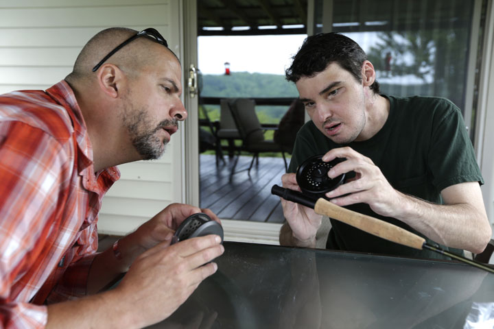Richard Norris, right, shows friend Andrew Kahle, left, how to load line into a fly fishing rod at Norris' in Hillsville, Va. The man whose face was disfigured by a gunshot spent 15 years as a recluse, but now the 37-year-old is doing things he never would have before. 