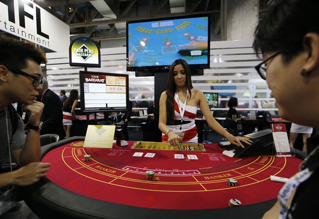 In this file photo taken on Thursday, May 23, 2013, an attendant demonstrates the game of baccarat on a baccarat gaming table during the Global Gaming Expo Asia in Macau.