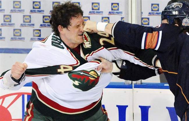 Minnesota Wild left wing Derek Boogaard (24) gets hit by Edmonton Oilers left wing Steve MacIntyre (33) in a fight during first period NHL hockey action in Edmonton on Jan. 30, 2009. 