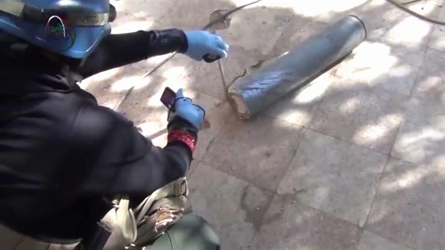 In this image taken from amateur video posted online, appearing to show a presumed UN staff member measuring and photographing a canister in the suburb of Moadamiyeh in Damascus, Syria, Monday Aug. 26, 2013. (Photo by Media Office of Moadamiyeh/AP Photo)