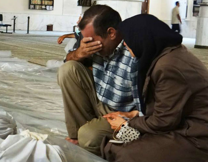 In this citizen journalism photo provided by the Local Committee of Arbeen, which has been authenticated based on its contents and other AP reporting, a man and woman mourn over the dead bodies of Syrian men after an alleged poisonous gas attack fired by regime forces, according to activists in Arbeen town, Damascus, Syria, .