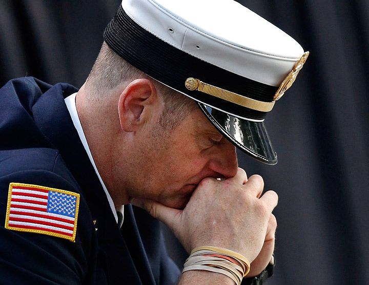 A firefighter pauses for a quiet moment as friends and relatives of the victims of 9/11 gather for a ceremony marking the 12th anniversary of the attacks at the National September 11 Memorial at the World Trade Center site, Wednesday, Sept. 11, 2013, in New York. (Photo credit: AP Photo)