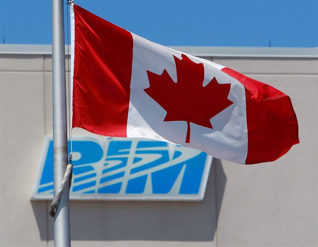 The Canadian flag flies in front of the Research In Motion (RIM) company logo on one of their buildings in Waterloo, Ont., on June 29, 2012.