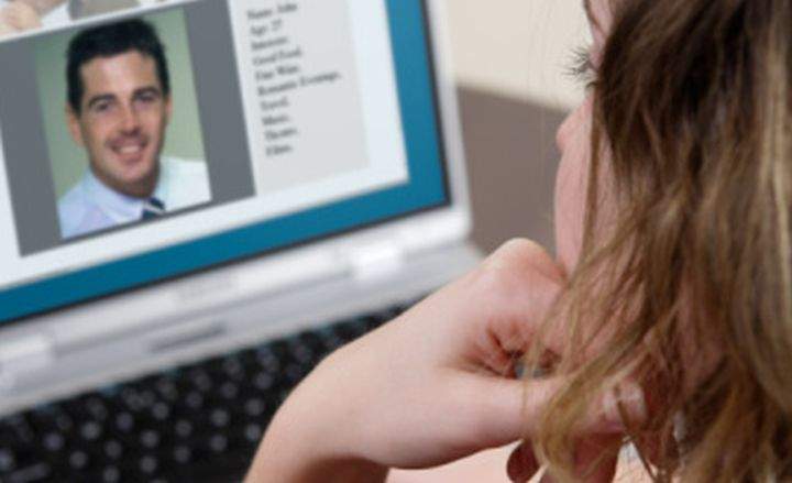 Young woman using laptop, dating agency site on screen.
