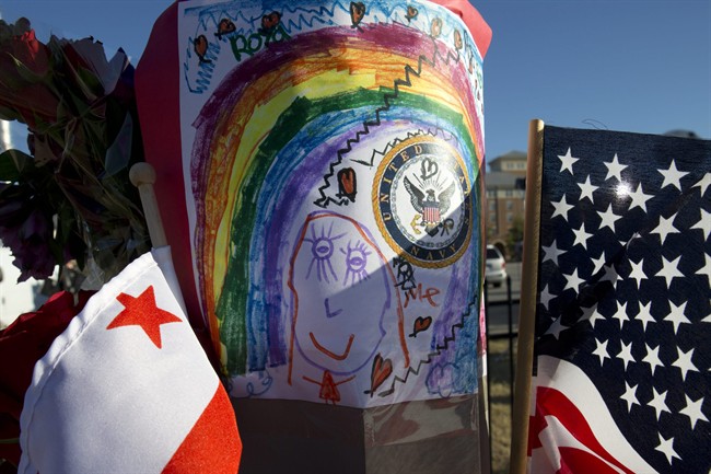 Across the street from the Washington Navy Yard, a child's drawing, the U.S. and D.C. flags, and a bouquet of flowers are taped to a post in a makeshift memorial to the victims two days after a gunman killed twelve people and was killed himself inside the Navy Yard in Washington, on Wednesday, Sept. 18, 2013. 