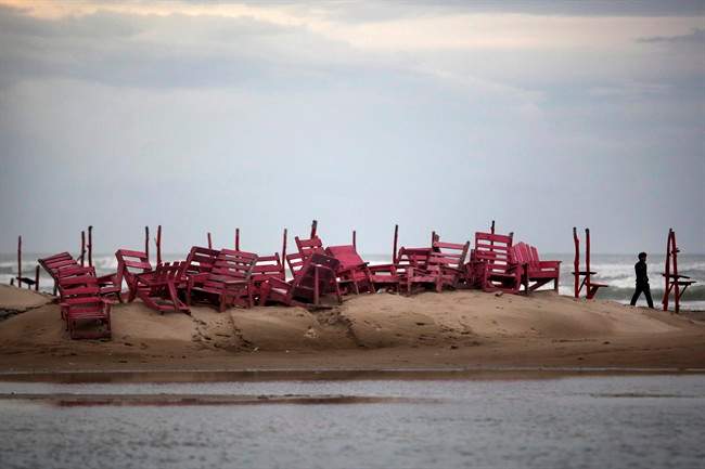 A man walks past tied up chairs at the Miramar beach as Hurricane Ingrid approaches the coast in Ciudad Madero, Mexico, Sunday Sept. 15, 2013. 