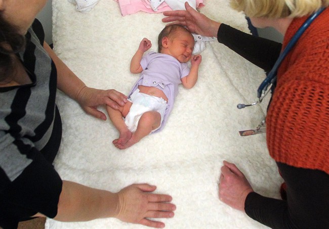 practitioner, right, examines a newborn girl accompanied by her mother in Portland, Ore.