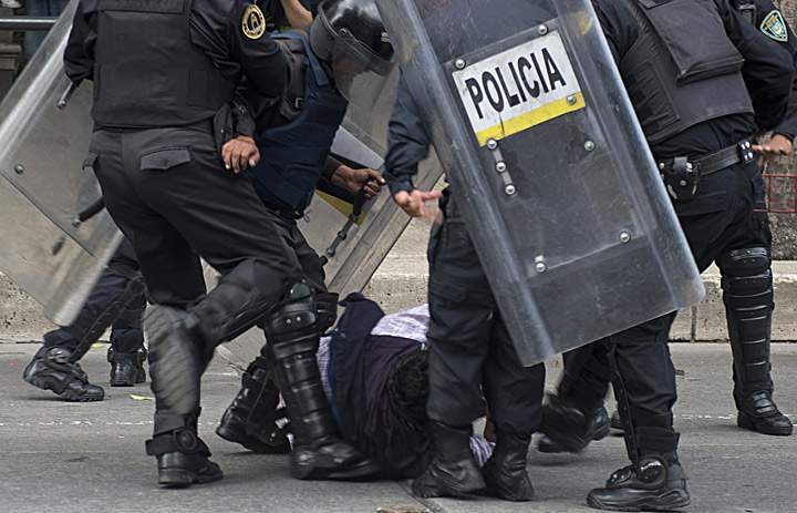 Riot policemen kick a teacher during clashes within a protest against the educational reform proposed by President Enrique Pena Nieto, along Reforma avenue in Mexico City on September 11, 2013. (Photo credit: Getty Images)