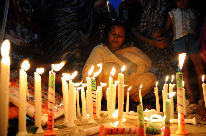Bangladeshi garment workers and relatives of victims of the Rana Plaza building collapse hold candles during a memorial at the site of the Rana Plaza garment factory building collapse in Savar, on the outskirts of Dhaka on October 24, 2013, the six-month anniversary of the disaster.