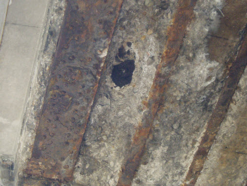 Photo of a hole in the bottom of the Dufferin Bridge from a Feb. 2008 report. The bottom of the asphalt surface is visible through a hole in the concrete.