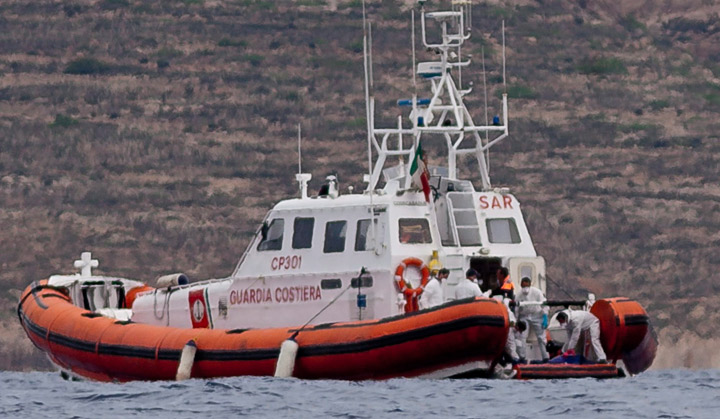 Italian Coast Guard personnel recover a body bag on their patrol boat in Lampedusa island, Italy, Tuesday, Oct. 8, 2013.