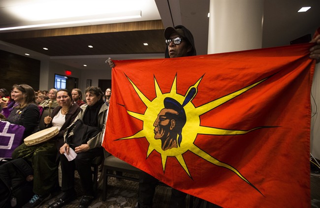 An indigenous man holds a flag during the National Energy Board public hearings on Enbridge Line 9 oil pipeline, in Toronto, Friday October 18, 2013. 