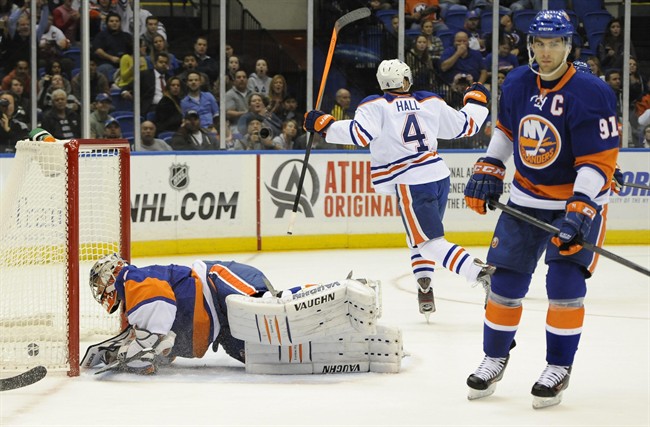 Edmonton Oilers' Taylor Hall (4) celebrates his second goal in the first period of an NHL hockey game as New York Islander' John Tavares (91) reacts and goalie Evgeni Nabokov (20) scrambles back up from the ice on Thursday, Oct. 17, 2013, in Uniondale, N.Y.