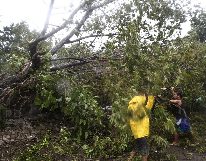 Residents clear a road after trees were toppled by strong winds at the onslaught of powerful typhoon Haiyan that hit the island province of Cebu, Philippines. (AP Photo/Chester Baldicantos)