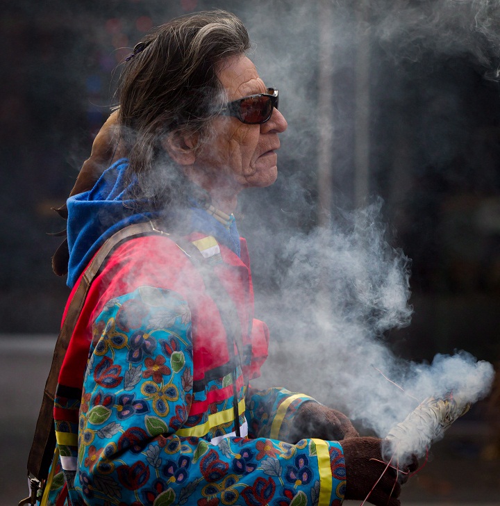 Robert Bonner, of the Nisichawayasihk Cree Nation in Nelson House, Man., is shrouded in smoke from burning sweetgrass while marching to a National Aboriginal Veterans Day ceremony at the Victory Square Cenotaph in Vancouver, on Friday November 8, 2013. (The Canadian Press/Darryl Dyckber)