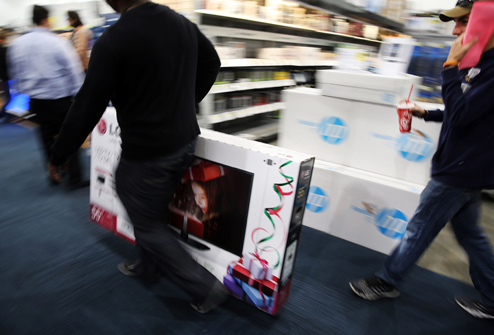 Black Friday shoppers carry away discounted items from at a Best Buy store which opened its doors at 6pm on Thanksgiving Day this year on November 29, 2013 in Naples, Florida. (Photo credit: Getty Images)