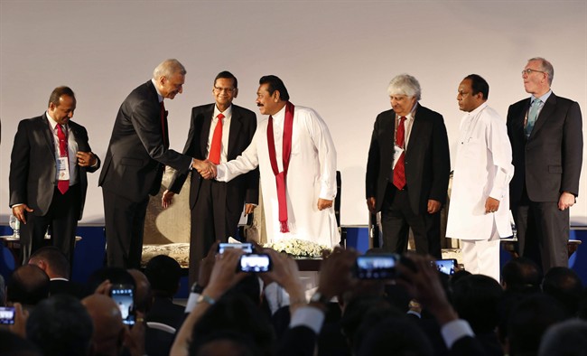 Sri Lankan President Mahinda Rajapaksa, center, shakes hands with Commonwealth Secretary-General Kamalesh Sharma as Sri Lankan Foreign Minister Gamini Lakshman Peiris, third left, and Commonwealth Business Forum (CBF) Chairman Mohan Kaul, third right, watch them during the inaugural session of the CBF in Colombo, Sri Lanka, Tuesday, Nov. 12, 2013. 