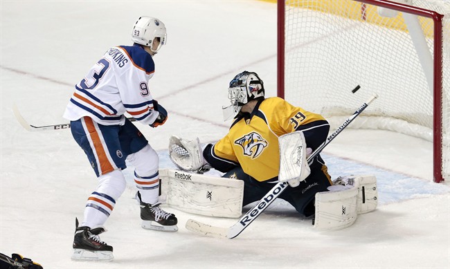 Edmonton Oilers forward Ryan Nugent-Hopkins, left, scores against Nashville Predators goalie Marek Mazanec (39), of Czech Republic, in the second period of an NHL hockey game Thursday, Nov. 28, 2013, in Nashville, Tenn. 
