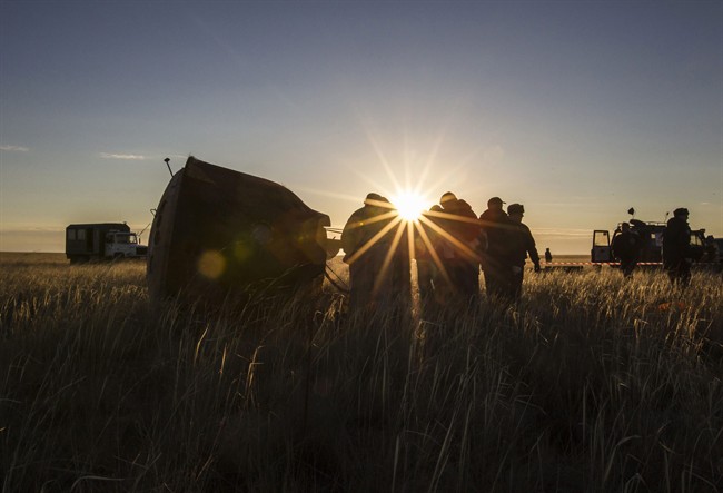 Search and rescue team members approach Soyuz TMA-09M capsule, left, carrying the International Space Station (ISS) crew, Fyodor Yurchikhin of Russia, Karen Nyberg of the United States and Luca Parmitano of Italy, that landed with a parachute in a remote area near the town of Zhezkazgan in central Kazakhstan Monday, Nov. 11, 2013. 