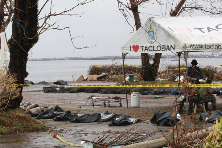 Members of the Philippine National Police talk amongst themselves next to body bags containing victims of Typhoon Haiyan on November 12, 2013 near Tacloban, Leyte, Philippines. (Photo credit: Getty Images)