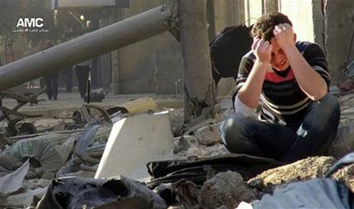 A Syrian man mourns as he sits in the rubble of buildings following a Syrian government airstrike in Aleppo, Syria.