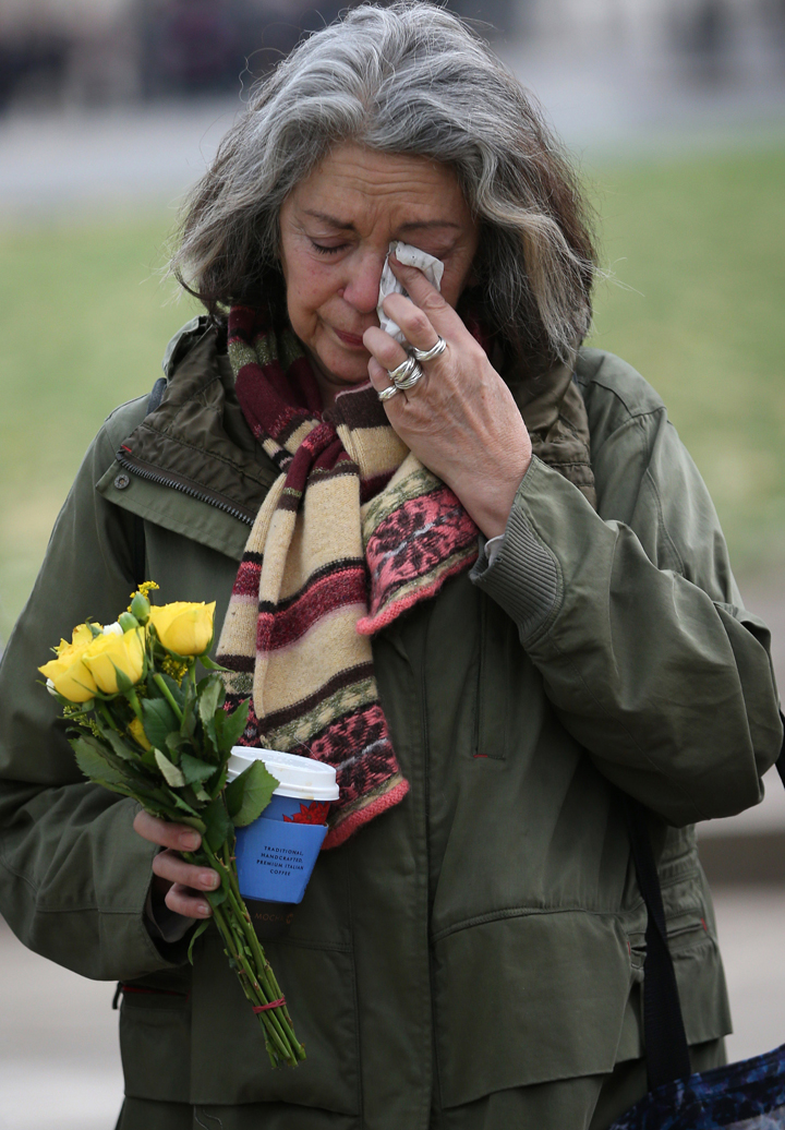 London:Joanna Vignola weeps before placing a floral tribute at the foot of a statue to Nelson Mandela in Parliament Square on December 6, 2013 in London, England. (Photo credit: Getty Images)