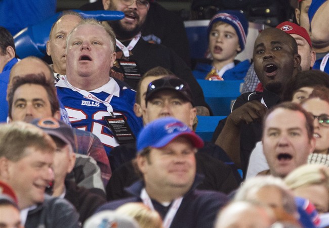 Toronto Mayor Rob Ford and his driver Jerry Agyemang, right, watch the Buffalo Bills play the Atlanta Falcons during the first half of NFL action in Toronto, Sunday December 1, 2013. THE CANADIAN PRESS/Mark Blinch