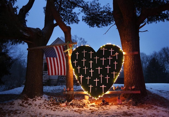 In this Saturday, Dec. 14, 2013, file photo, a makeshift memorial with crosses for the victims of the Sandy Hook massacre stands outside a home in Newtown, Conn., the one-year anniversary of the shootings. 