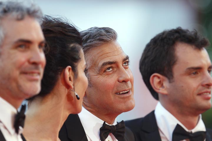 George Clooney gestures as he poses for photographers with Alfonso Cuaron, Sandra Bullock, and screenwriter Jonas Cuaron at the Venice Film Festival. (AP Photo/Andrew Medichini)