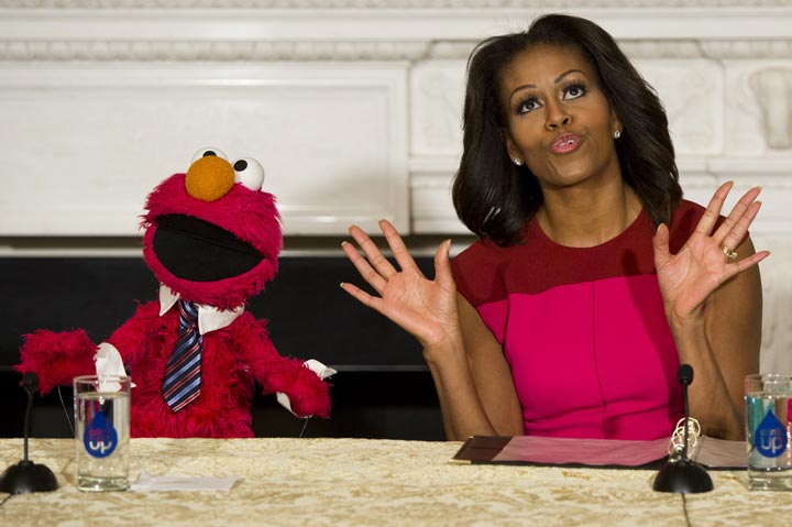U.S. First Lady Michelle Obama dances alongside Sesame Street character Elmo.