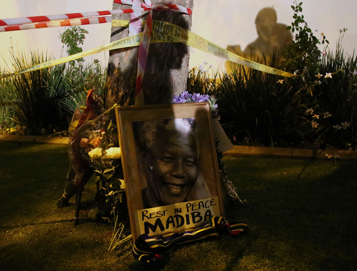 This picture shows a framed image of former South African president Nelson Mandela as people pay tributes following his death, in Johannesburg on Dec. 6, 2013.  (Photo credit: Getty Images)