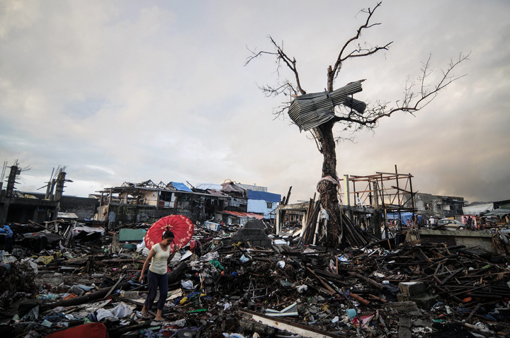 A typhoon survivor walks along debris of destroyed houses in Tacloban, Philippines, December 24, 2013. (Photo credit: AP Photo)