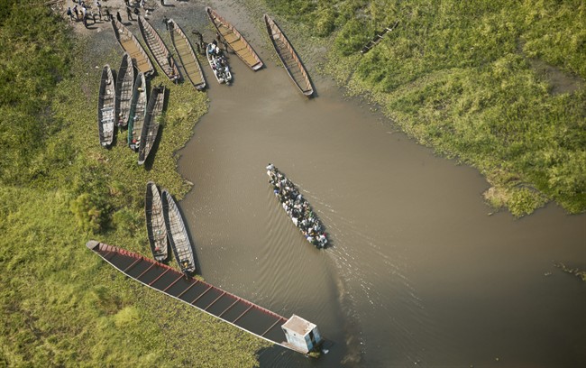 In this Monday, Dec. 30, 2013 file photo, a boat packed with passengers arrives at a dock after crossing a waterway near the town of Malakal, the capital of Upper Nile State.