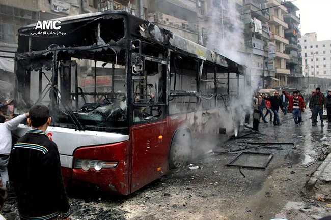 This citizen journalism image provided by Aleppo Media Center AMC which has been authenticated based on its contents and other AP reporting, shows Syrians inspecting a burnt bus after a missile fired by Syrian government aircraft hit the vehicle in the rebel-held neighborhood of al-Bab in Aleppo, Syria, Tuesday, Dec. 31, 2013. 