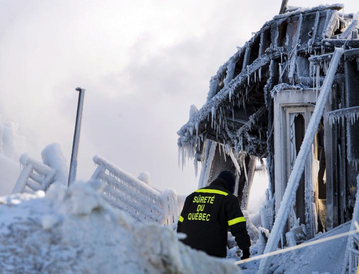 A police investigator looks over the frozen rubble after a fatal fire destroyed a seniors residence in L’Isle-Verte, Que., Thursday, January 23, 2014. (Ryan Remiorz/The Canadian Press)