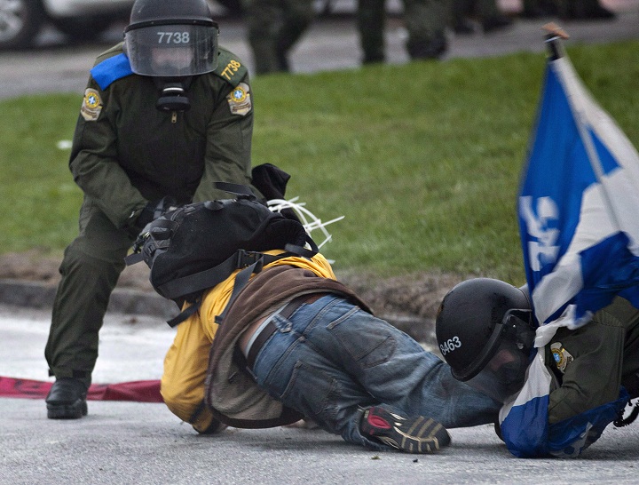 Two riot police officers tackle a demonstrator outside a Quebec Liberal Party meeting Friday, May 4, 2012 in Victoriaville, Que.