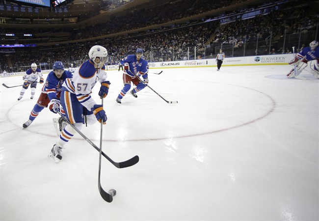 New York Rangers' Derick Brassard (16) chases Edmonton Oilers' David Perron (57) for control of the puck during the first period of an NHL hockey game on Thursday, Feb. 6, 2014, in New York. 