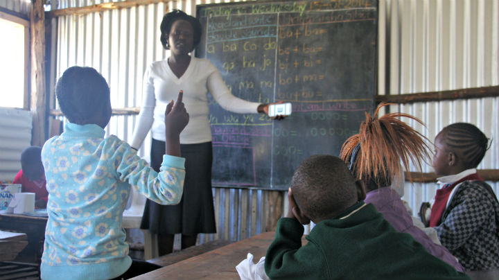 A teacher uses a smartphone to conduct vision test on students at a school in Kenya.