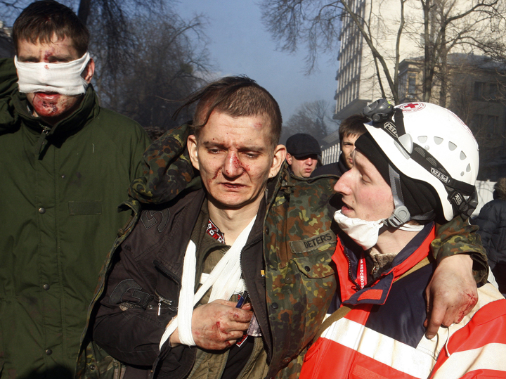 Anti-government protesters carry a wounded man during clashes with riot police in Kyiv on Feb. 18, 2014. (Photo credit: Yury Kirnichny/Getty Images)
